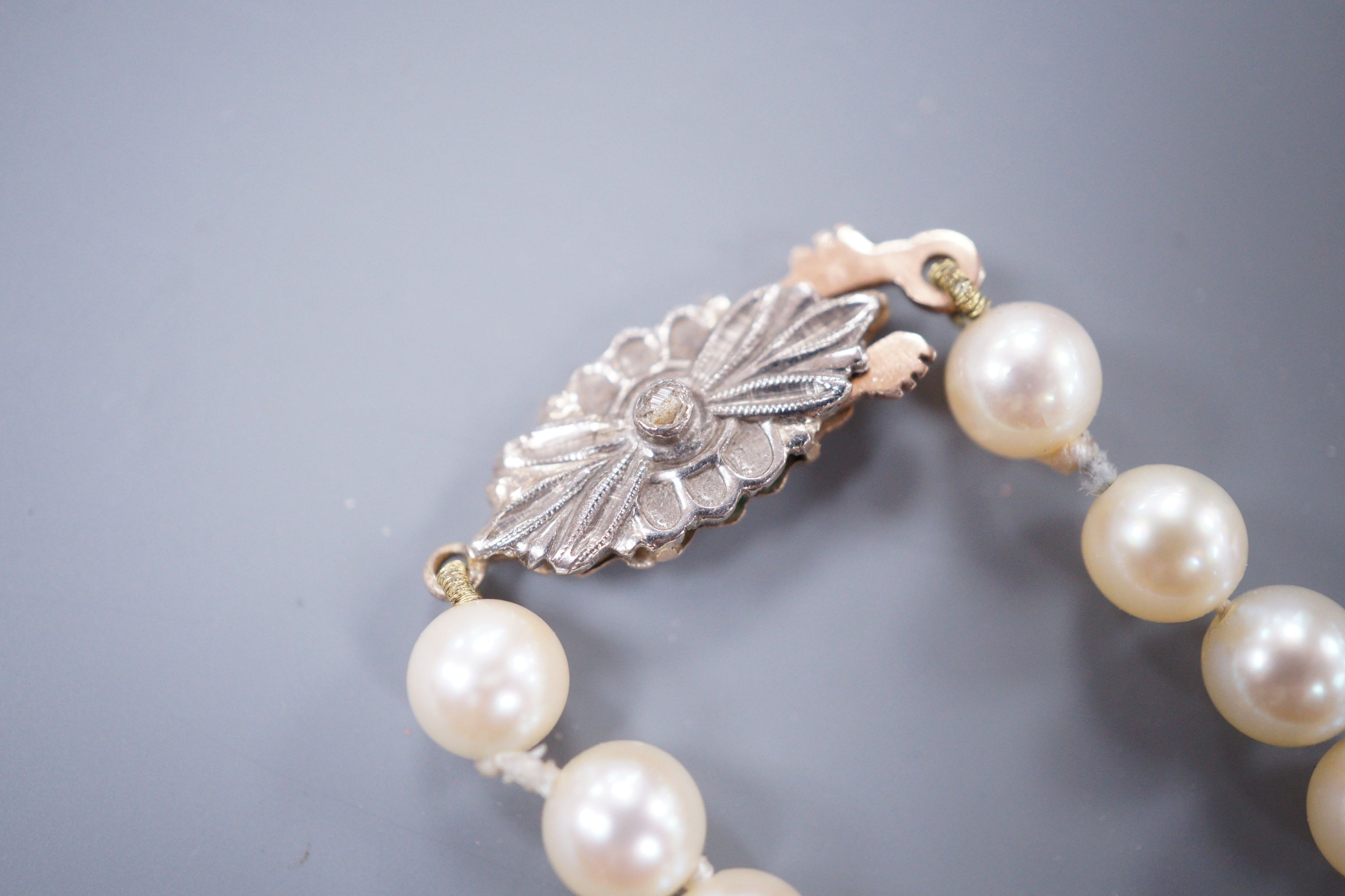A single strand graduated cultured pearl necklace, with rose cut diamond set yellow metal clasp, 52cm.